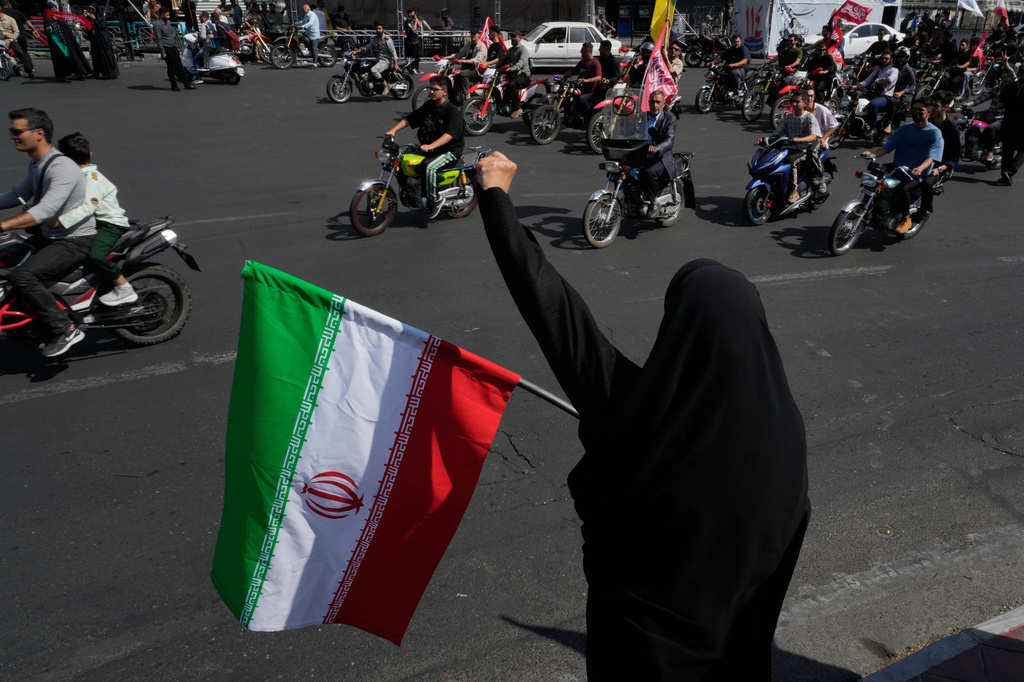 A woman chants slogan as she holds an Iranian flag while motorcyclists ride during a state-organized motorcycle parade called "Janfada," meaning "Sacrifice for Iran,", in Tehran, Iran, Friday, Sept. 25, 2026. (AP Photo/Vahid Salemi)