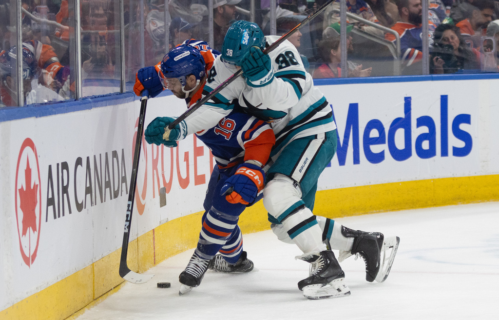 San Jose Sharks' Mario Ferraro (38) and Edmonton Oilers' Jason Dickinson (16) battle for the puck during second period NHL action, in Edmonton, on Tuesday March 17, 2026. (Jason Franson/The Canadian Press via AP)