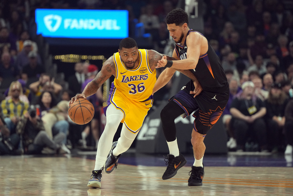 Los Angeles Lakers guard Marcus Smart (36) drives past Phoenix Suns guard Devin Booker during the first half of an NBA basketball game, Tuesday, Dec. 23, 2025, in Phoenix. (AP Photo/Rick Scuteri)