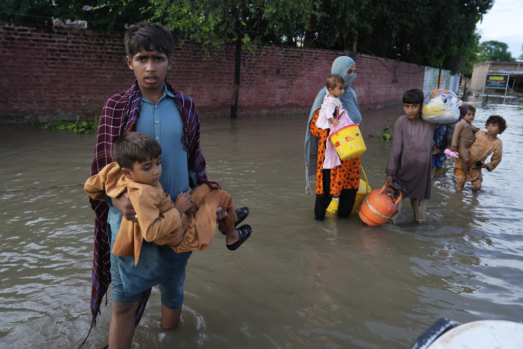 FILE - A family wades through flood waters to a rescue boat after levels in the Sutlej river rose following release of water from overflowing dams in neighboring India, in Kasur district, Pakistan, Aug. 26, 2025. (AP Photo/K.M. Chaudary, File)