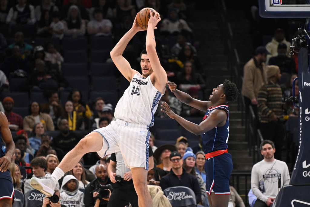 Memphis Grizzlies center Zach Edey (14) grabs a high pass as Los Angeles Clippers guard Cam Christie defends during the first half of an NBA basketball game, Friday, Dec. 5, 2025, in Memphis, Tenn. (AP Photo/John Amis)
