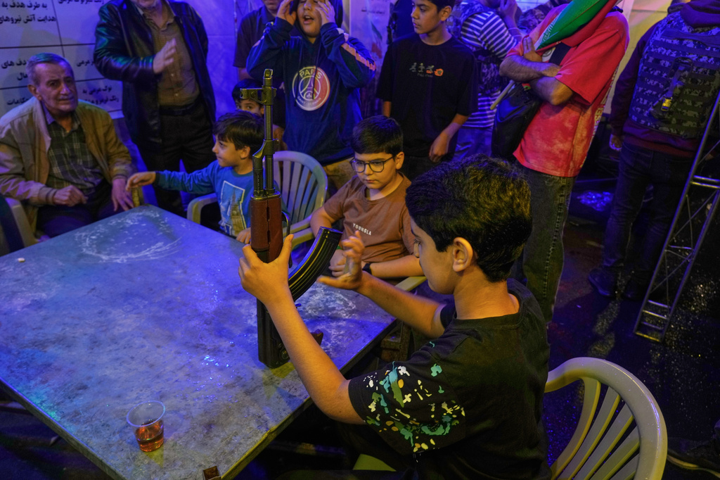 A boy handles a Kalashnikov-style assault rifle during a weapons training class led by members of the Revolutionary Guard's volunteer Basij force in Tehran, Iran, Tuesday, May 19, 2026. (AP Photo/Vahid Salemi)