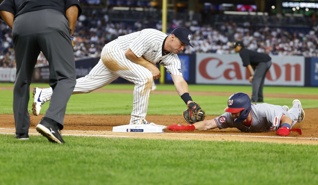 New York Yankees first baseman Paul Goldschmidt, center, picks off Washington Nationals' Jacob Young, right, for an out during the third inning of a baseball game, Monday, Aug. 25, 2025, in New York. (AP Photo/Noah K. Murray)