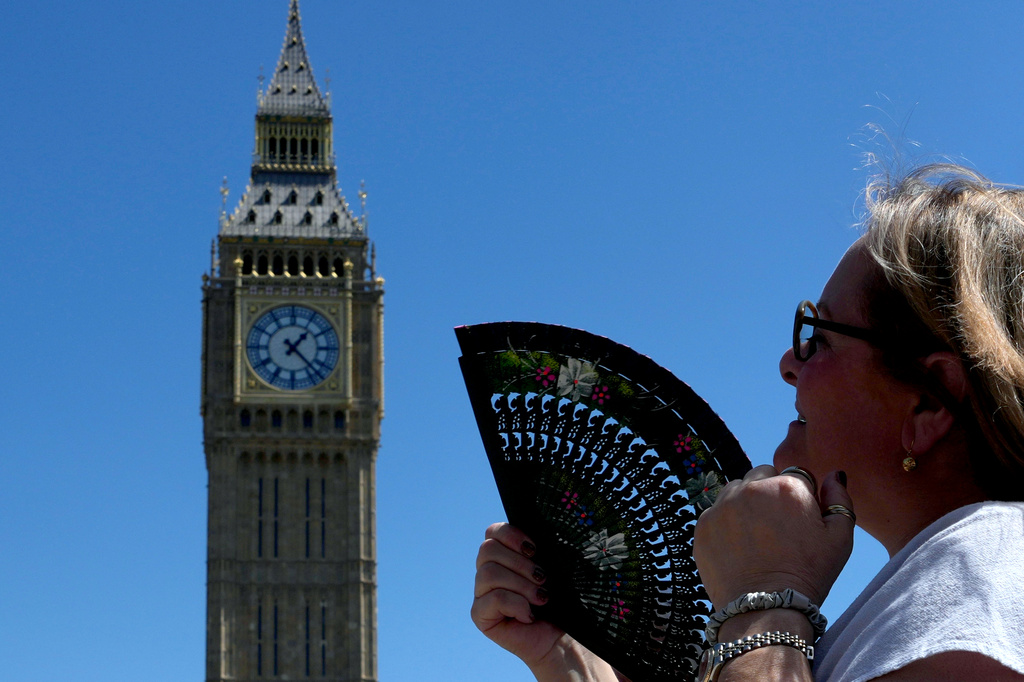 FILE - A woman cools herself outside the Palace of Westminster in London, May 26, 2026. (AP Photo/Kin Cheung, File)