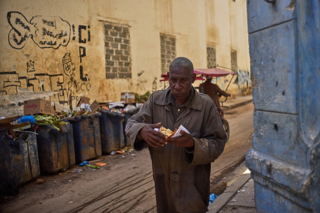 A pedestrian eats a slice of pizza in Havana, Cuba, Wednesday, Feb. 11, 2026. (AP Photo/Ramon Espinosa)