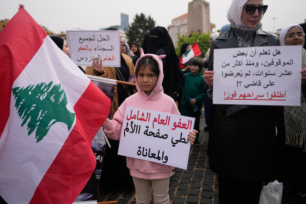 A child holds a placard reading in Arabic, "A comprehensive general amnesty to turn the page on pain and suffering," during a protest demanding a general amnesty for Islamic groups and other prisoners, in downtown Beirut, Lebanon, Friday, Jan. 30, 2026. (AP Photo/Hassan Ammar)