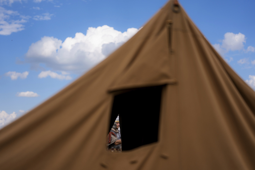 A man of the Legio X Gemina Coh II, Roman era military historical group with members from the Czech Republic and Slovakia, stands behind a tent in Poiana, Romania, Saturday, July 12, 2025, during the Getodava historical reenactment festival. (AP Photo/Andreea Alexandru)