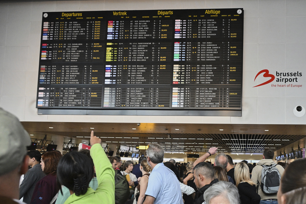 An airport employee points at a departure board after a cyber attack caused delays at Brussels International Airport in Zaventem, Belgium, Saturday, Sept. 20, 2025. (AP Photo/Harry Nakos)