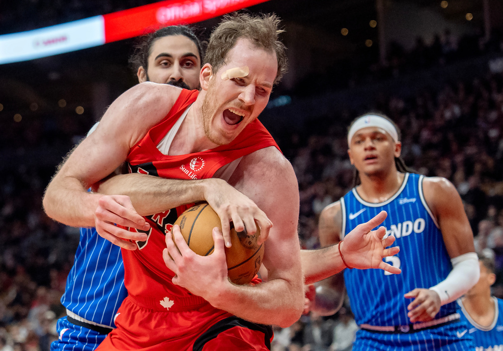 Toronto Raptors centre Jakob Poeltl (front) is fouled by Orlando Magic centre Goga Bitadze (back left) as Magic forward Paolo Banchero (right) looks on during first half NBA action in Toronto on Sunday, March 29, 2026. (Frank Gunn/The Canadian Press via AP)