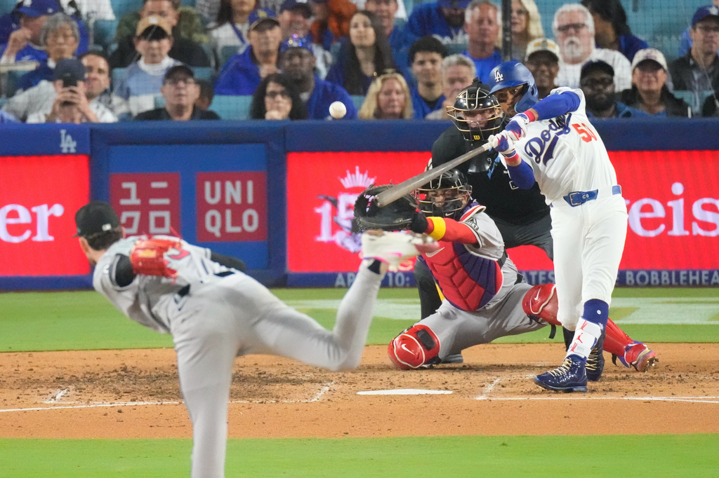 Los Angeles Dodgers' Mookie Betts, right, hits a three-run home run as Arizona Diamondbacks starting pitcher Ryne Nelson, left, and catcher Gabriel Moreno watch during the third inning of a baseball game Friday, March 27, 2026, in Los Angeles. (AP Photo/Mark J. Terrill)