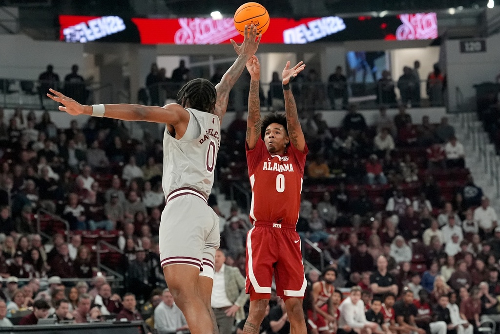 Alabama guard Labaron Philon (0) shoots a three-point shot past Mississippi State forward Jamarion Davis-Fleming (0) during the first half of an NCAA college basketball game, Tuesday, Jan. 13, 2026, in Starkville, Miss. (AP Photo/Rogelio V. Solis)