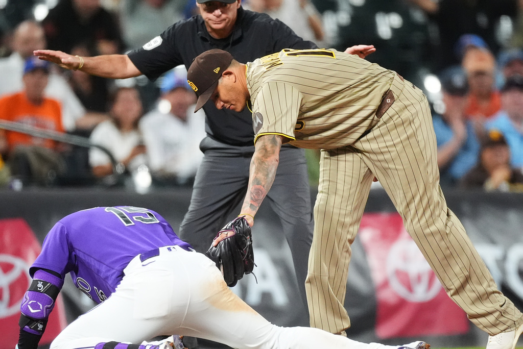 Colorado Rockies' Hunter Goodman, front left, slides into third base for a triple as San Diego Padres third baseman Manny Machado, front right, applies a late tag while third base umpire Andy Fletcher makes the call in the sixth inning of a baseball game Monday, Sept. 14, 2026, in Denver. (AP Photo/David Zalubowski)