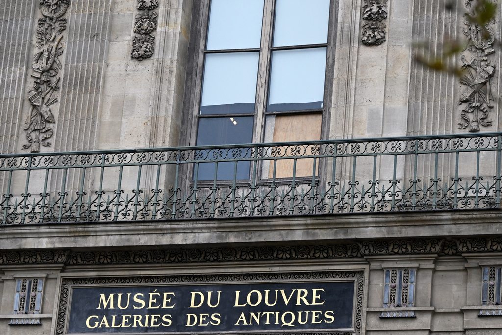A plywood board covers the window where thieves entered the Louvre museum the day before to steal historic jewels, Monday, Oct. 20, 2025, in Paris. (AP Photo/Emma Da Silva)