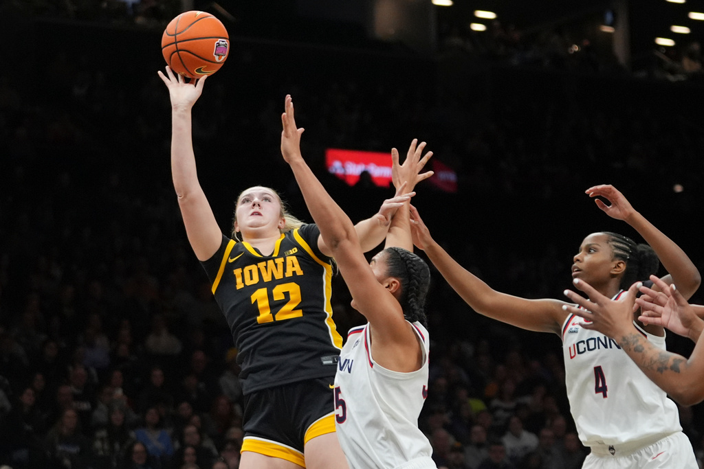 Iowa's Layla Hays (12) shoots over UConn's Azzi Fudd and Blanca Quinonez (4) during the first half of an NCAA college basketball game Saturday, Dec. 20, 2025, in New York. (AP Photo/Frank Franklin II)