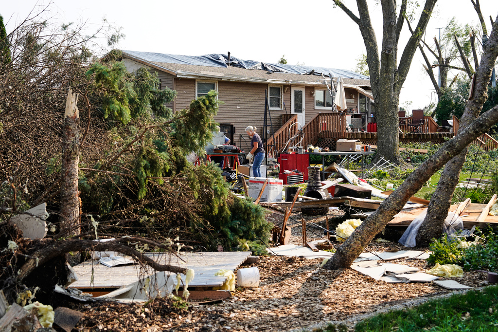 People clean up debris in front of a damaged home after a tornado struck the day before, Tuesday, July 28, 2026, in Appleton, Wis. (AP Photo/Kayla Wolf)