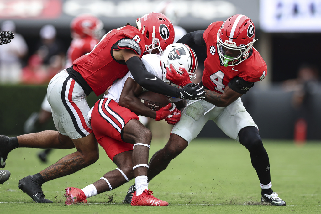 Georgia defensive backs Joenel Aguero, left, and KJ Bolden (4) tackle Austin Peay wide receiver Nate Garnett Jr., center, during the first half of an NCAA college football game, Saturday, Sept. 6, 2025, in Athens, Ga. (AP Photo/Colin Hubbard)
