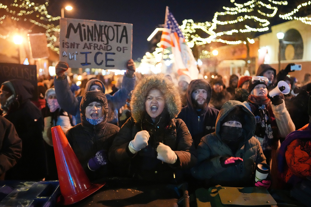 Protesters chant and bang on trash cans as they stand behind a makeshift barricade during a protest in response to the death of 37-year-old Alex Pretti, who was fatally shot by a U.S. Border Patrol officer earlier in the day, Saturday, Jan. 24, 2026, in Minneapolis. (AP Photo/Adam Gray)