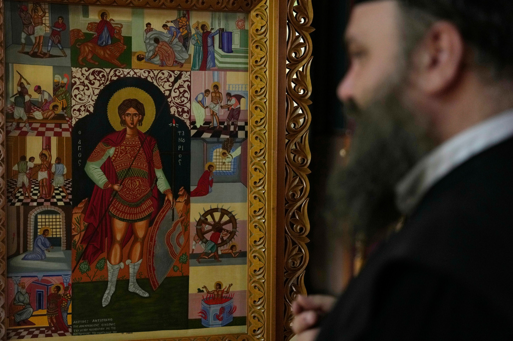 Father Nikolaos Vlavianos stands beside an icon of Saint Fanourios, known in Greek as "The Revealer," at the Church of St. Fanourios in Athens, Tuesday, Aug. 25, 2026. (AP Photo/Thanassis Stavrakis)