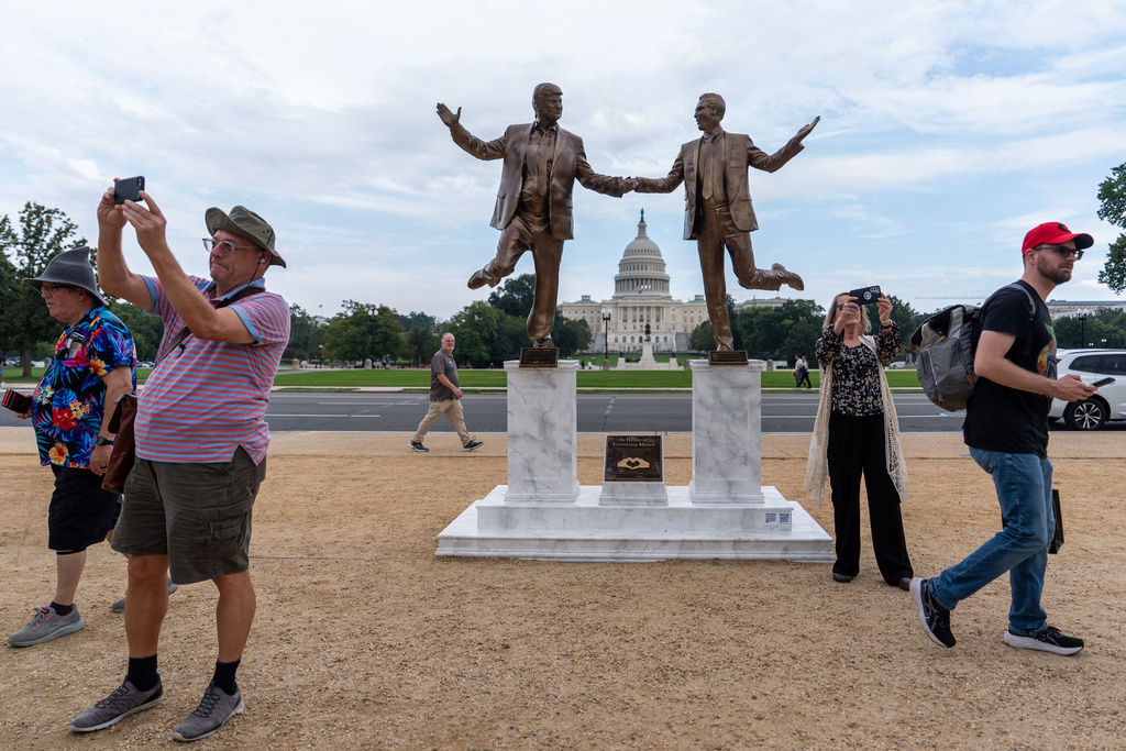 FILE - Visitors take photos backdropped by a bronze painted sculpture depicting President Donald Trump and disgraced financier Jeffrey Epstein, on the National Mall near the Capitol in Washington, Sept. 23, 2025. (AP Photo/Julia Demaree Nikhinson, File)
