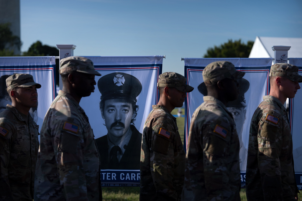 U.S. Army soldiers walk past a portrait of New York firefighter Peter Carroll at a Steel Across America event with the Tunnel to Towers Foundation on the Ellipse, Tuesday, Sept. 8, 2026, in Washington. (AP Photo/Mark Schiefelbein)