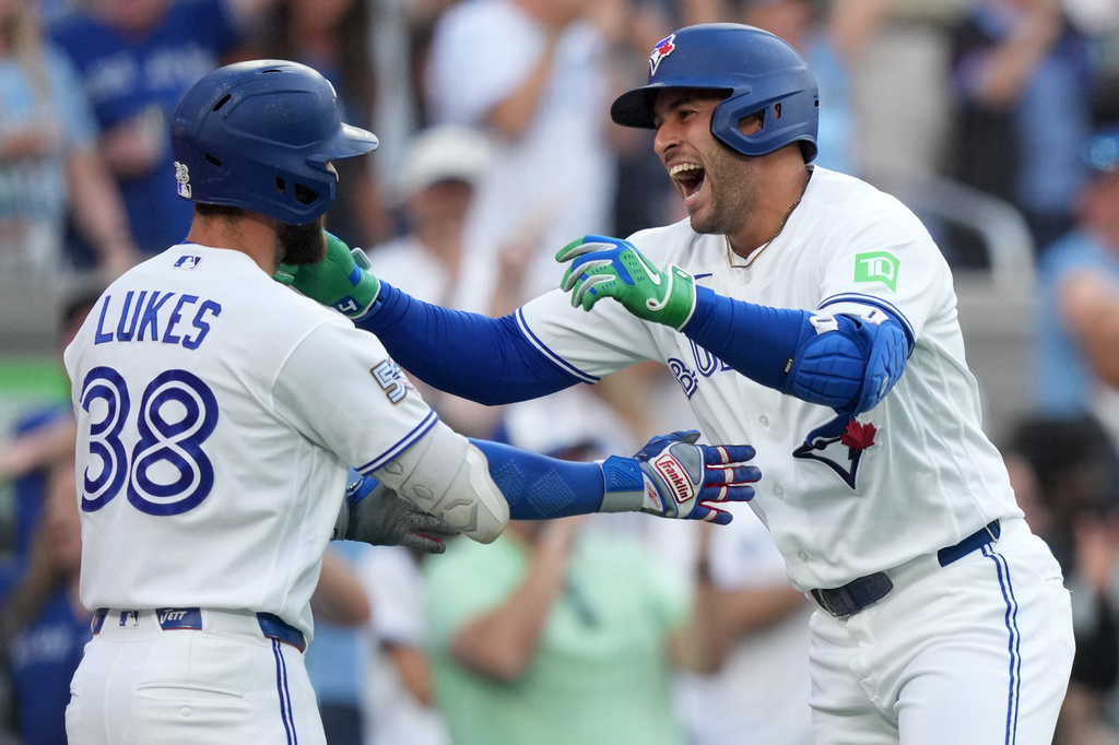 Toronto Blue Jays designated hitter George Springer, right, celebrates with teammate Nathan Lukes (38) as he comes in to score after hitting a triple on an in-field home run after a fielding error by New York Mets' A.J. Ewing during the first inning of a baseball game in Toronto, Monday, June 29, 2026. (Nathan Denette/The Canadian Press via AP)