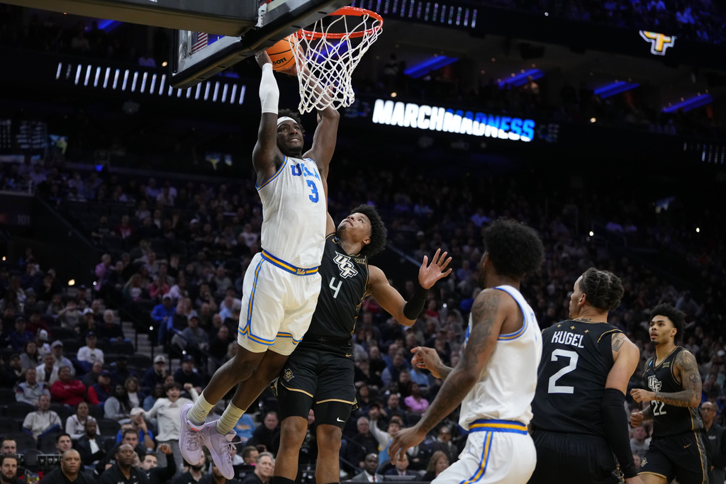 UCLA's Eric Dailey Jr., left, goes up for a dunk past UCF's Jamichael Stillwell during the first half in the first round of the NCAA college basketball tournament, Friday, March 20, 2026, in Philadelphia. (AP Photo/Matt Slocum)
