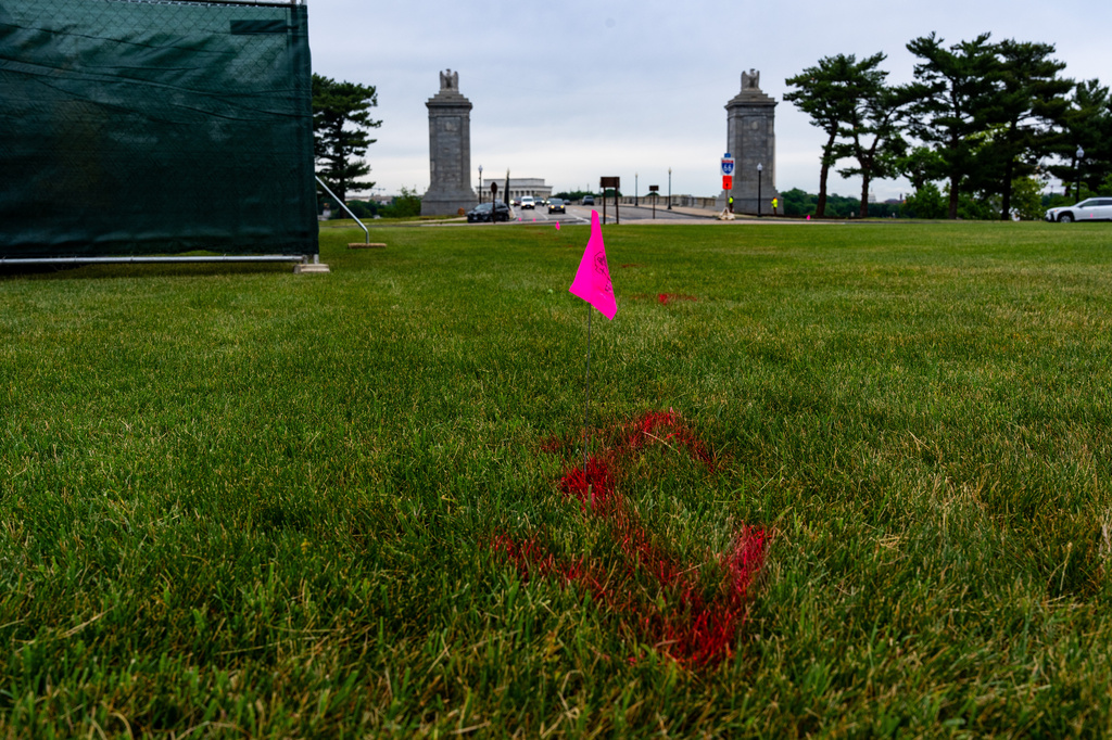 FILE - Flags are placed as workers survey the Memorial Circle, where President Donald Trump has proposed building an arch to commemorate the United States' 250th anniversary, May 11, 2026, in Washington. (AP Photo/Alex Brandon, File)