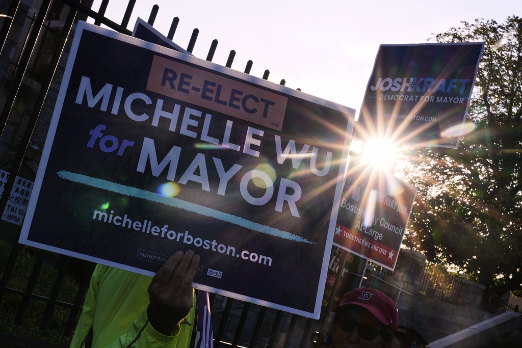 Sunrise peeks through campaign signs of Boston Mayor Michelle Wu and challenger Josh Kraft at a polling place, Tuesday, Sept. 9, 2025, in the Roslindale neighborhood of Boston. (AP Photo/Charles Krupa)