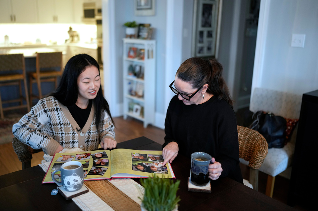 Zoie Albers and her adoptive mother, Leslie Albers, right, look through family photographs at their home in Piperton, Tenn., on Saturday, Jan. 17, 2026. (AP Photo/George Walker IV)