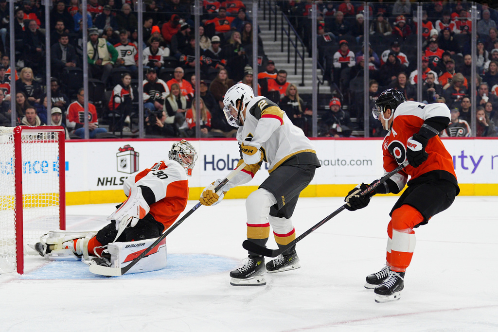 Vegas Golden Knights' Zach Whitecloud, center, scores a goal past Philadelphia Flyers goaltender Dan Vladar and Travis Konecny (11) during the first period of an NHL hockey game, Thursday, Dec. 11, 2025, in Philadelphia. (AP Photo/Derik Hamilton)
