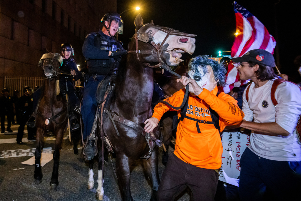 Police on horseback disperse a crowd of protesters, during a "No Kings" protest Saturday, Oct. 18, 2025. (AP Photo/Ethan Swope)