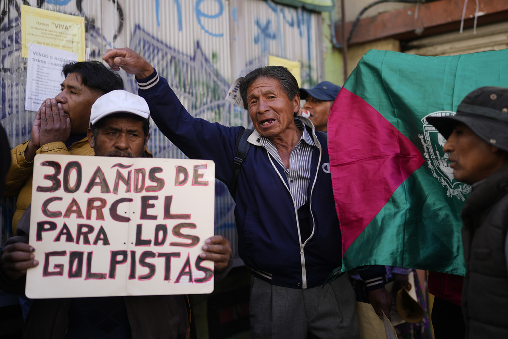 A protester holds a sign that reads in Spanish, "30 years in prison for the coup plotters" as suspended governor of Santa Cruz Luis Fernando Camacho attends a court hearing regarding the length of his pretrial detention stemming from the crisis over the 2019 ouster of former President Evo Morales, in La Paz, Bolivia, Tuesday, Aug. 26, 2025. (AP Photo/Juan Karita)