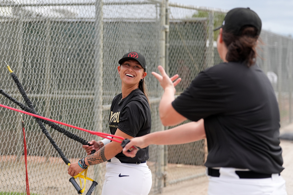 Kelsie Whitmore talks with another player as they use resistance bands during a Women's Pro Baseball League (WPBL) practice, Wednesday, March 18, 2026, in Fort Myers, Fla. (AP Photo/Rebecca Blackwell)