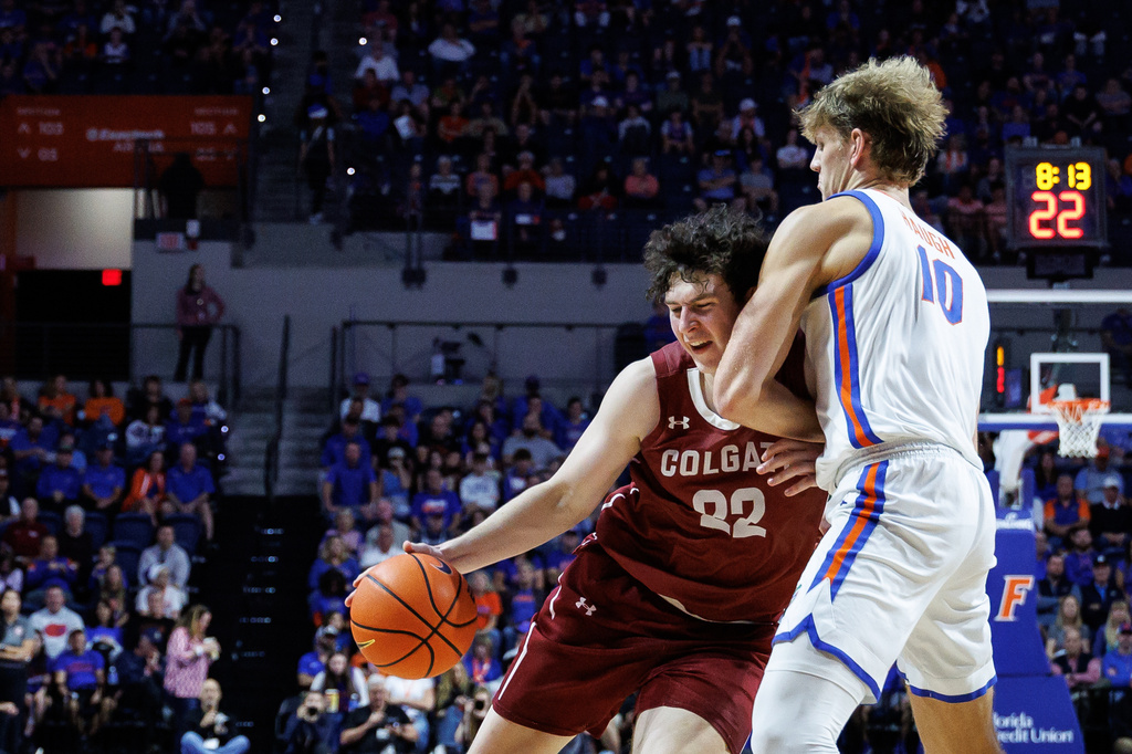 Colgate forward Sam Wright (33) charges Florida forward Thomas Haugh (10) during the first half of an NCAA college basketball game Sunday, Dec. 21, 2025, in Gainesville, Fla. (AP Photo/Chris Watkins)