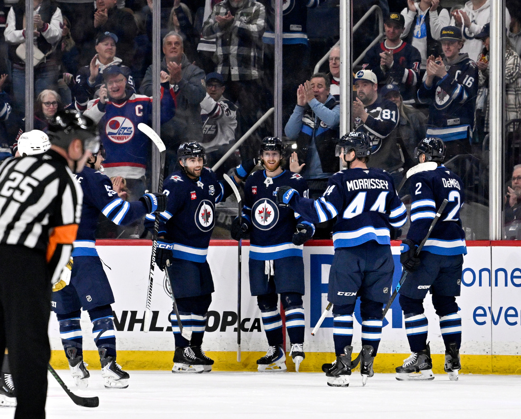 Winnipeg Jets' Kyle Connor (81) celebrates his goal against the Vegas Golden Knights with teammates Alex Iafallo (9), Josh Morrissey (44) and Dylan DeMelo (2) during the first period of their NHL hockey game in Winnipeg, Tuesday March 24, 2026. (Fred Greenslade/The Canadian Press via AP)