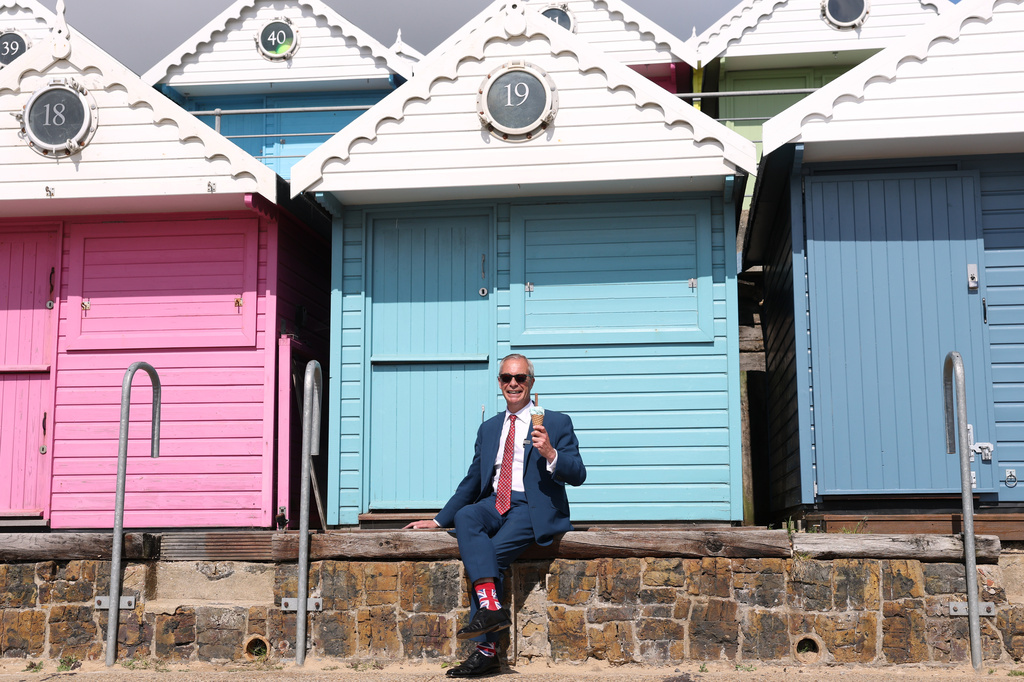 Britain's Reform Party leader Nigel Farage poses for photographers with an ice-cream on the beach after casting his vote at a polling station in Walton on the Naze, England, Thursday, May 7, 2026.(AP Photo/Richard Pelham)