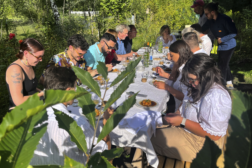 Visitors attend a joint meal at Martin Roetzel's 'The Monk Garden' in Berlin, Germany, Sunday, Aug. 17, 2025. (AP Photo/Fanny Brodersen)