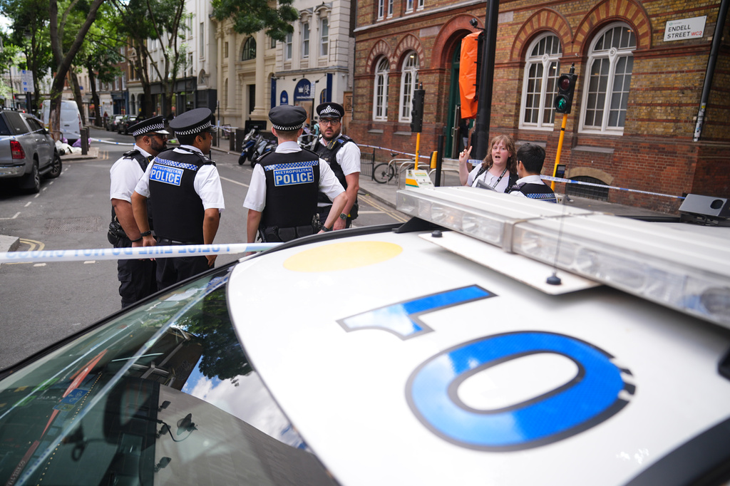 Police officers stand at the scene on Endell Street in Covent Garden, after four men were stabbed, in central London, Wednesday Aug. 5, 2026. PA Photo. (James Manning/PA via AP)