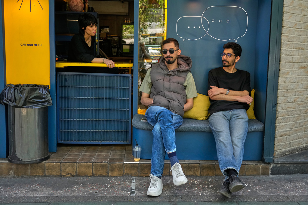 A cafe attendant sits at the counter as two men sit at a cafe in downtown Tehran, Iran, Sunday, April 5, 2026. (AP Photo/Vahid Salemi)