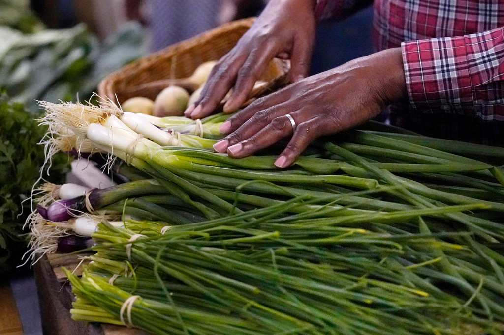 FILE - A farmer rests his hands on vegetables at a market June 15, 2023, in Manchester, N.H. (AP Photo/Charles Krupa, File)