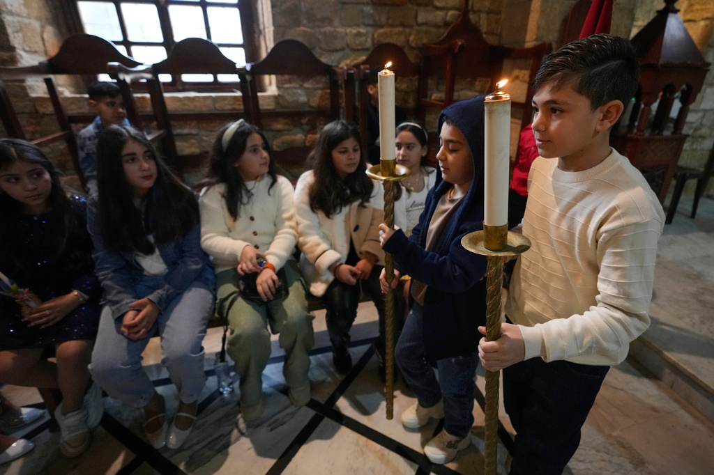 Boys hold candles during Palm Sunday Mass procession at Saint Thomas Cathedral, in the southern port city of Tyre, south Lebanon, Sunday, March 29, 2026. (AP Photo/Hussein Malla)