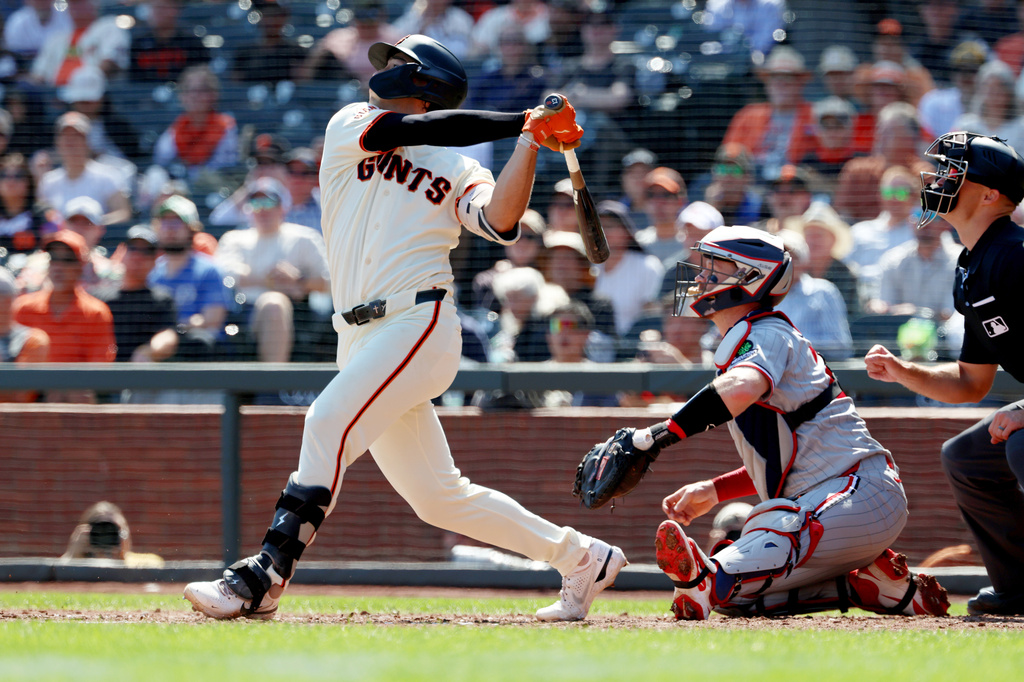San Francisco Giants' Shay Whitcomb hits a two-run single in front of Minnesota Twins catcher Ryan Jeffers, right, during the fourth inning of a baseball game in San Francisco, Wednesday, Sept. 23, 2026. (AP Photo/Jed Jacobsohn)