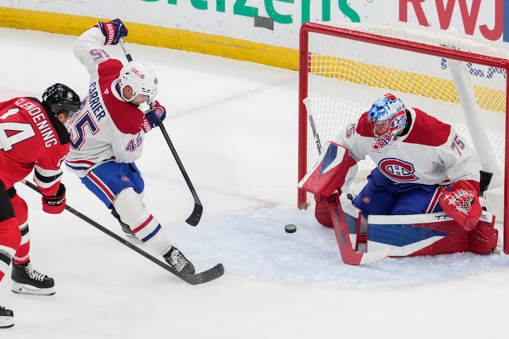 Montreal Canadiens goaltender Jakub Dobes (75) protect the net from New Jersey Devils center Luke Glendening (14) during the first period of an NHL hockey game, Thursday, Nov. 6, 2025, in Newark, N.J. (AP Photo/Yuki Iwamura)