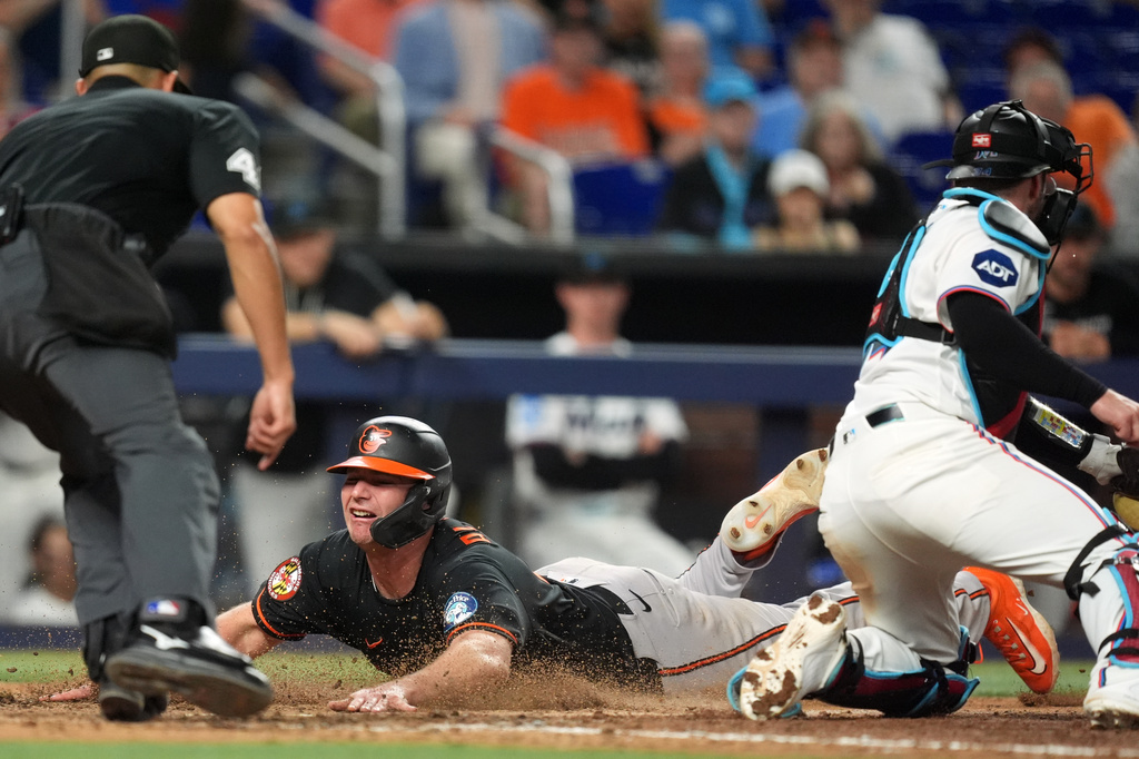 Baltimore Orioles' Pete Alonso, center, scores past Miami Marlins catcher Liam Hicks, right, on a single by Leody Taveras, during the ninth inning of a baseball game, Tuesday, May 5, 2026, in Miami. (AP Photo/Rebecca Blackwell)