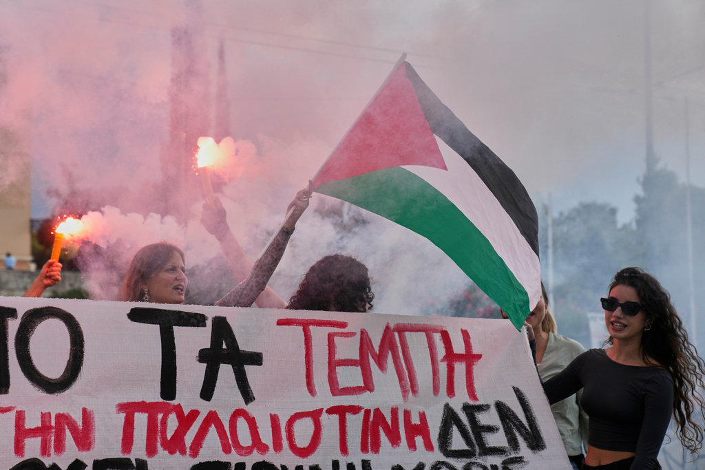 Protesters with flares wave a Palestinian flag during a nationwide 24-hour strike, as labor unions demand higher wages and the withdrawal of a bill that changes work hours Wednesday, Oct. 1, 2025. (AP Photo/Petros Giannakouris)