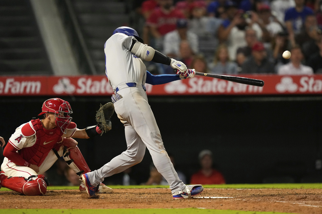 Los Angeles Dodgers' Shohei Ohtani, right, hits a solo home run as Los Angeles Angels catcher Logan O'Hoppe watches during the ninth inning of a baseball game Tuesday, Aug. 12, 2025, in Anaheim, Calif. (AP Photo/Mark J. Terrill)
