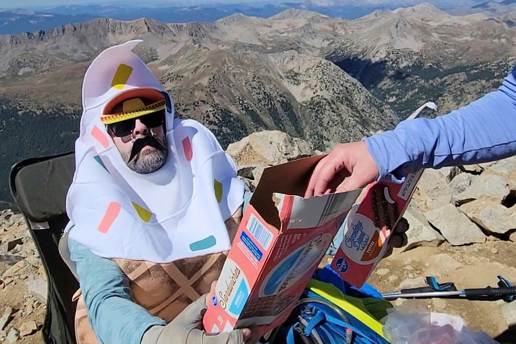 In this photo provided by Blaine Griffin, a man shares ice cream he carried up Huron Peak packed in dry ice with fellow hikers in Chaffee County, Colo., Sunday, Aug. 31, 2025. (Blaine Griffin via AP)