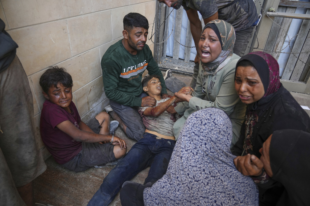 People mourn over the body of a young Palestinian killed while trying to reach trucks carrying humanitarian aid en route to Gaza City, outside the Hamad Al-Qatari Hospital in Beit Lahiya, northern Gaza Strip, Friday, Aug. 1, 2025. (AP Photo/Jehad Alshrafi)
