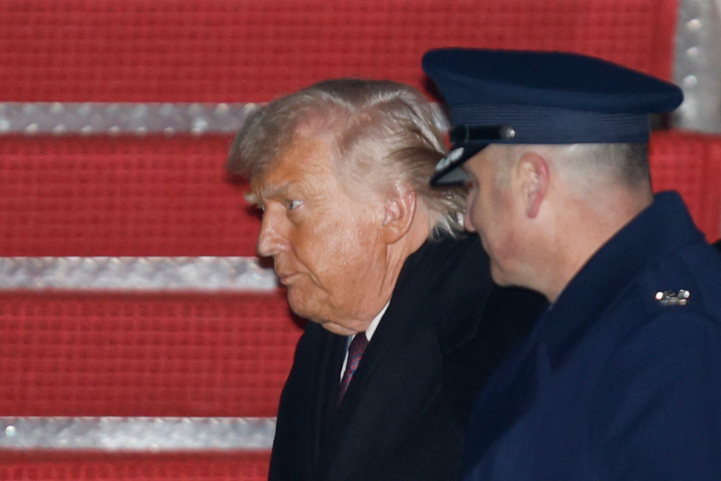 President Donald Trump, left, is greeted by Air Force Col. Christopher M. Robinson, commander of the 89th Airlift Wing, right, after walking down the stairs of Air Force One, upon his arrival at Joint Base Andrews, Md., Thursday, Jan. 22, 2026, after returning from the World Economic Forum in Davos, Switzerland.(AP Photo/Luis M. Alvarez)