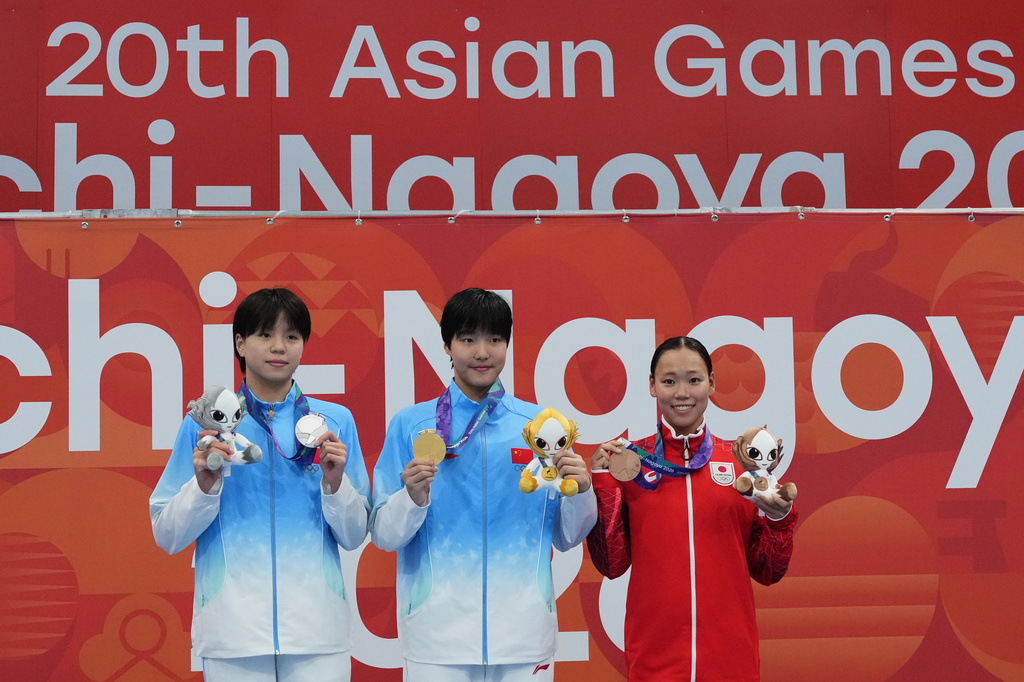 Gold medalist Yu Zidi of China, center, flanked by silver medalist Chang Mohan of China, left, and bronze medalist Misa Okuzono of Japan pose on the podium after the women's 200-meter butterfly final in swimming at the Asian Games in Tokyo, Japan, Sunday, Sept. 20, 2026. (AP Photo/Hiro Komae)